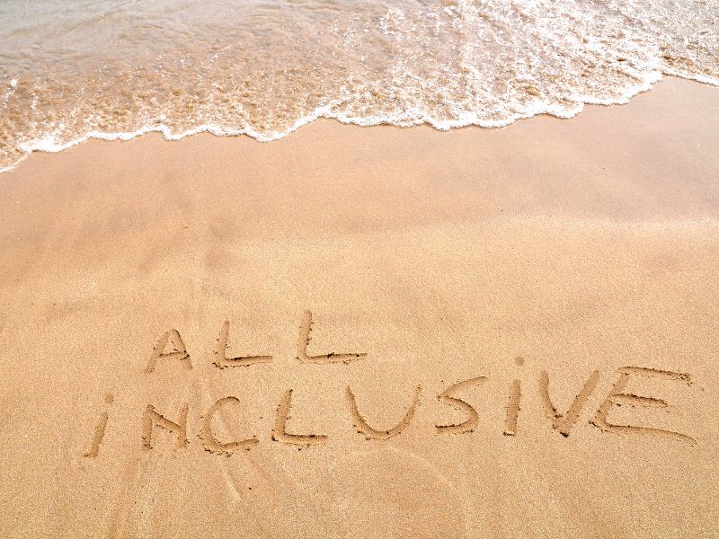 all inclusive written in sand on a sunny beach