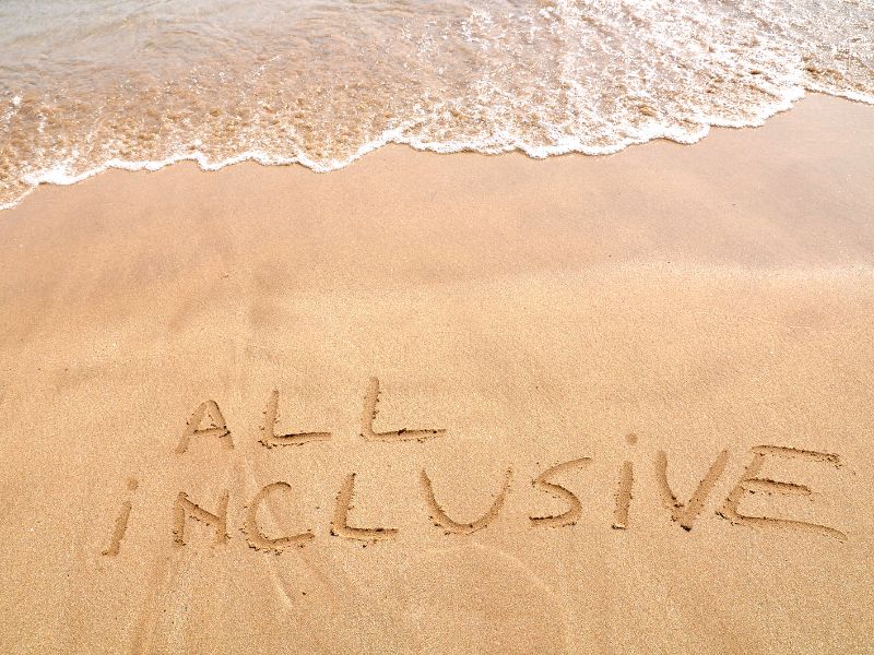 all inclusive written in sand on a sunny beach
