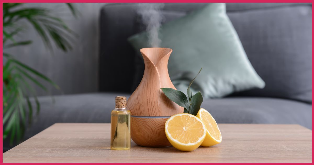 Wooden aroma diffuser emitting fragrance, with citrus oil in a glass bottle and lemon halves on the table.