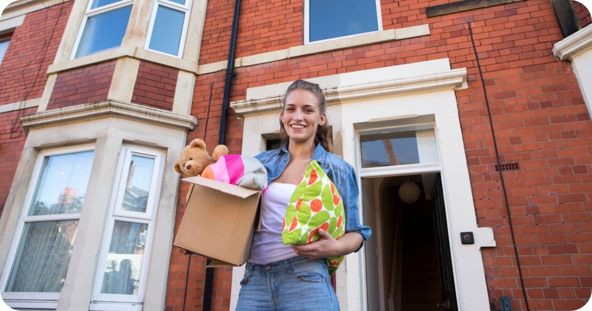 Student standing outside her new accommodation waiting to move in